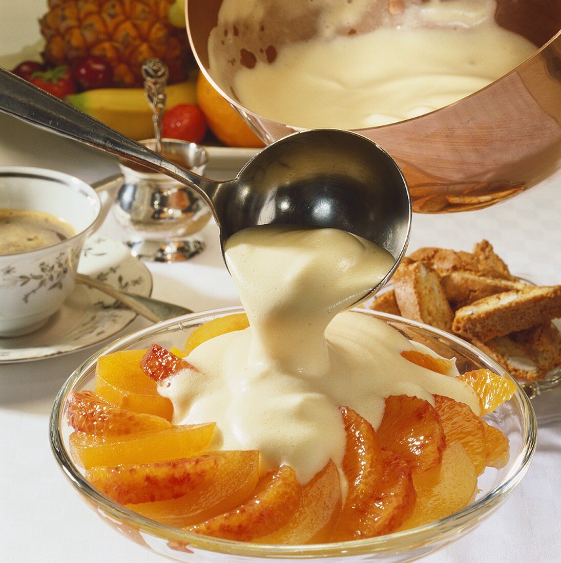 Zabaione (Weinschaumcreme) wird über Orangenfilets gegossen