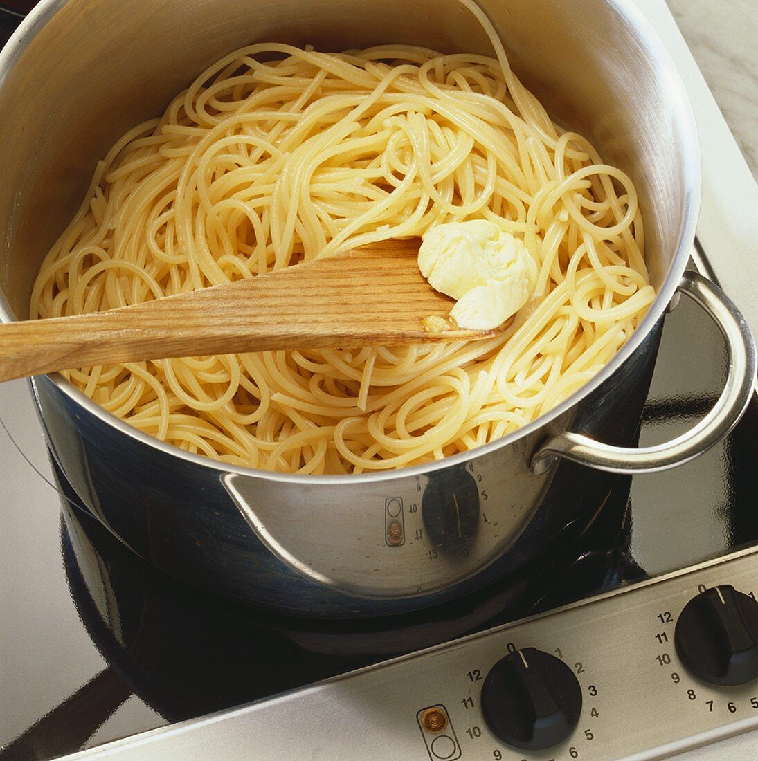Putting butter on cooked pasta