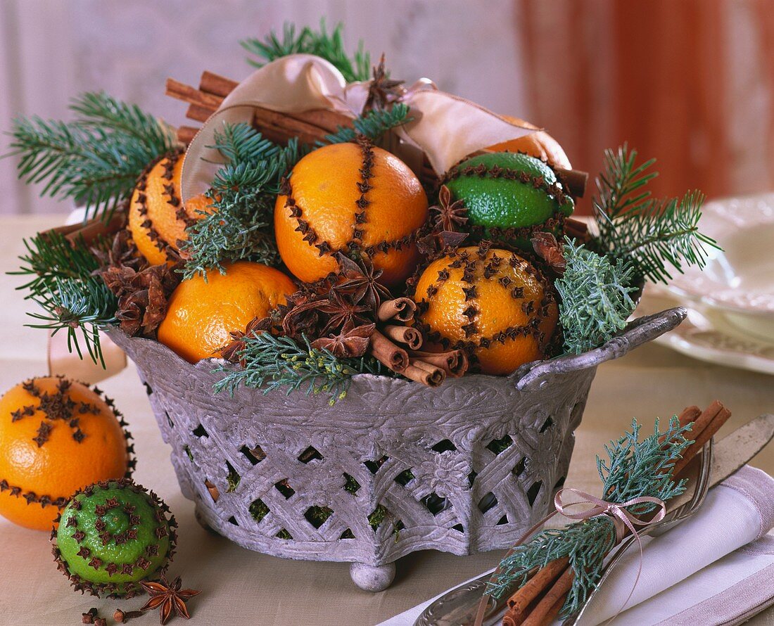 Bowl of citrus fruit studded with cloves, spices & greenery