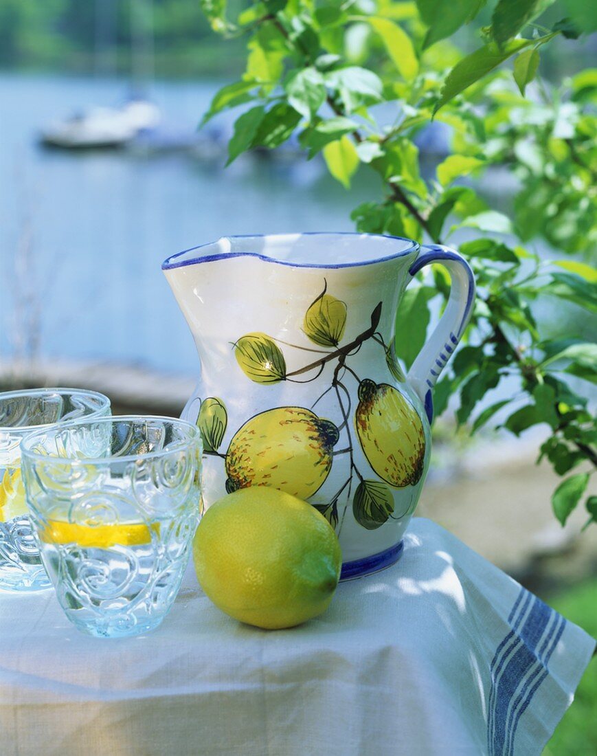 Fresh lemon, jug with lemon motif, water with lemon slices