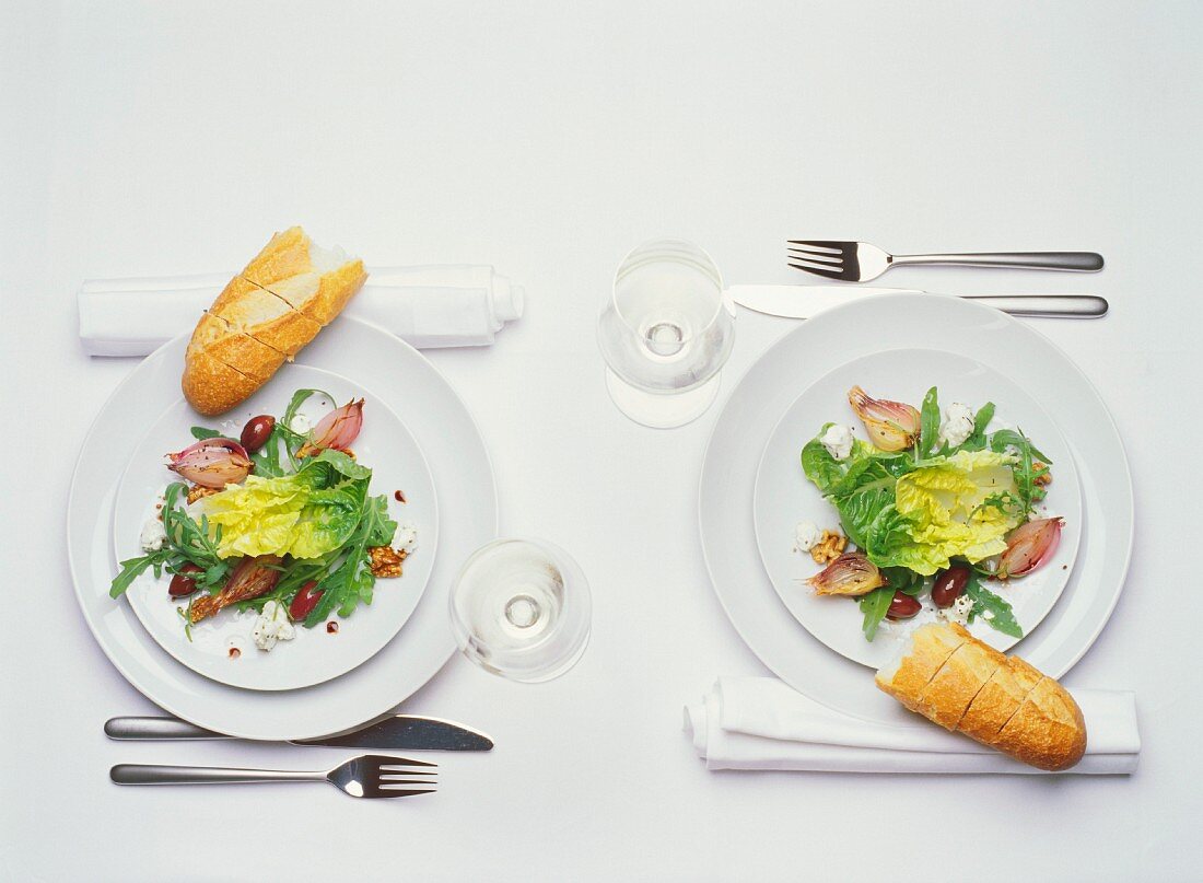 Gedeckter Tisch für zwei Personen (mit Salat und Baguette)
