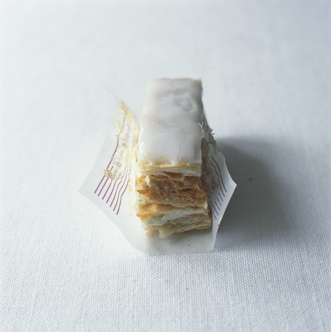 Iced, filled puff pastry slices in paper