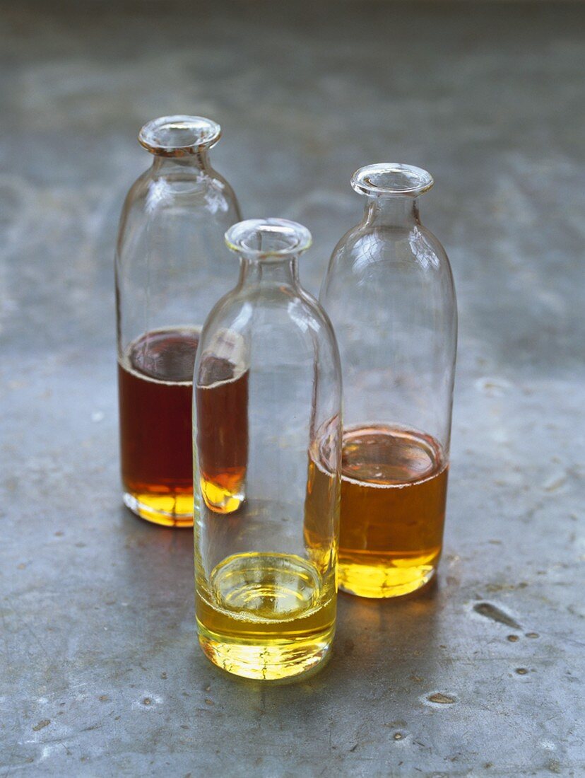 Drei verschiedene Öle in Glasflaschen