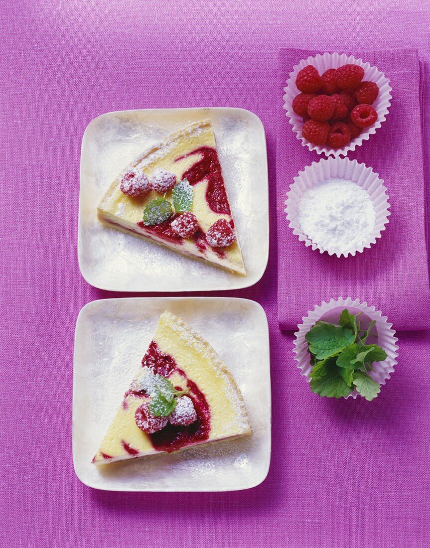 Two pieces of raspberry tart on square, white plates