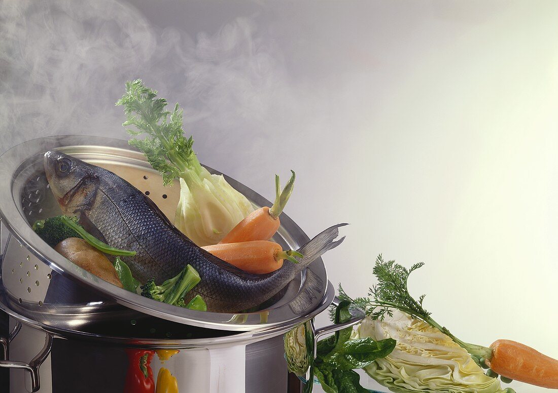 Fish and vegetables in the steamer insert of a pan