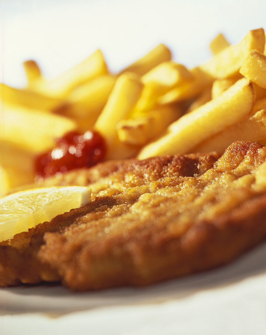 Paniertes Schnitzel mit Zitrone, Pommes und Ketchup