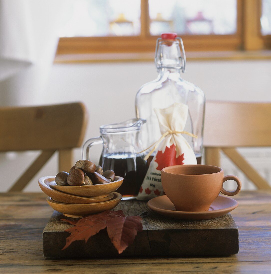 Tasse, Schälchen mit Esskastanien & Ahornsirup auf Tisch
