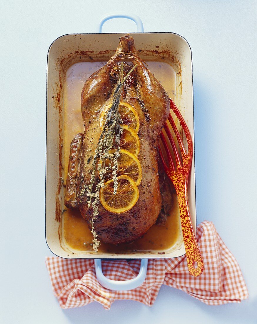A whole roast duck with slices of orange