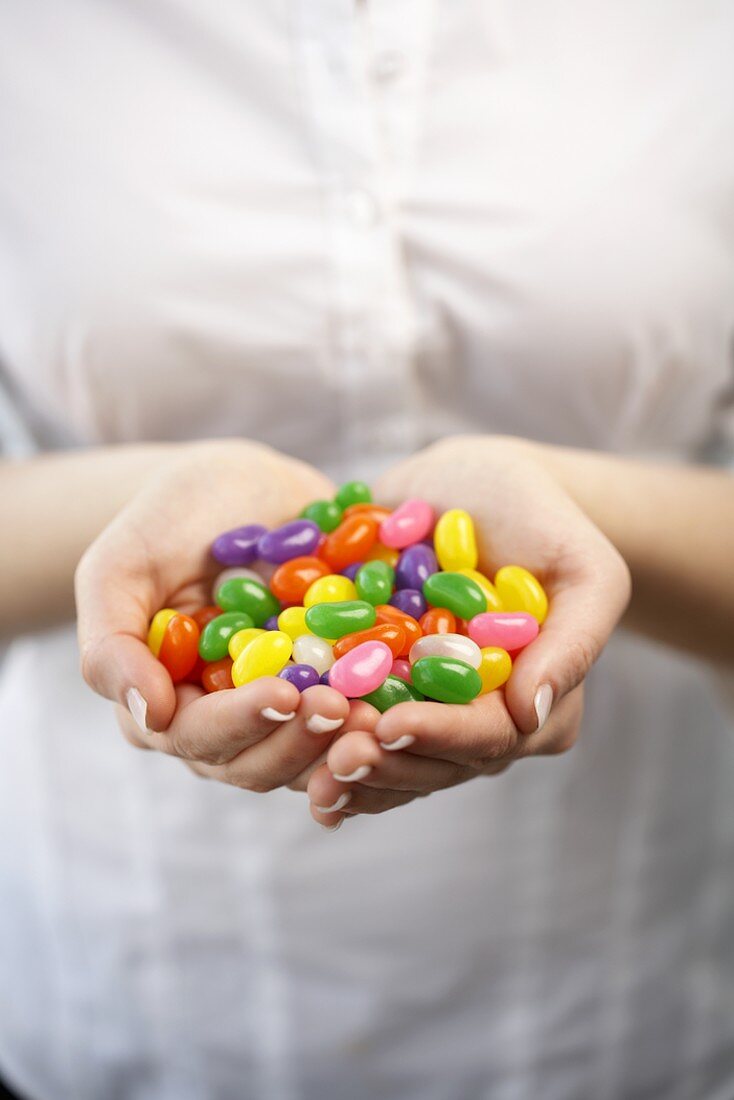 Junge Frau hält Hand voll Jelly Beans