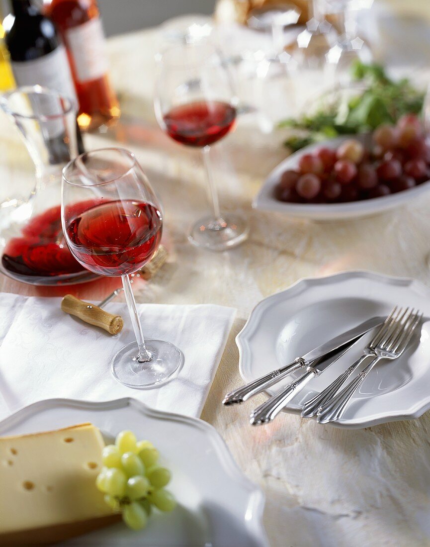 Ein gedeckter Tisch mit Käse, Weintrauben und Wein