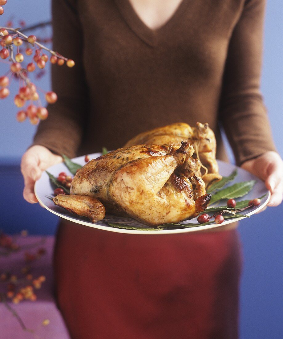 Hands holding roast turkey on a platter