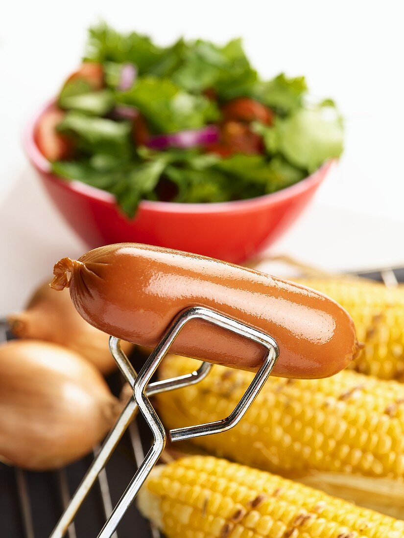 Eine Grillwurst in der Grillzange