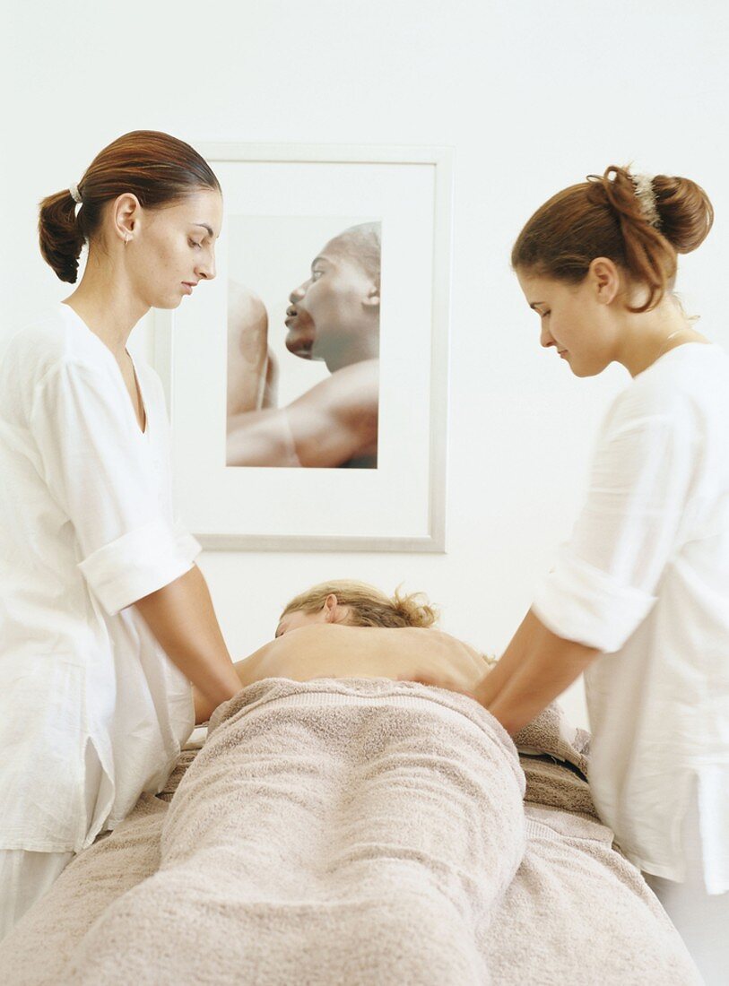 A woman being massaged by two other women