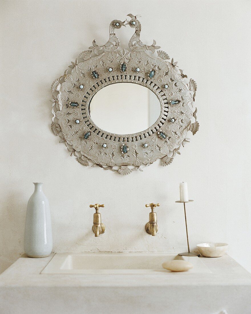 A wash basin with an ornately decorated mirror
