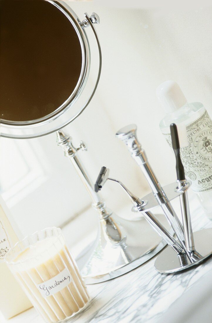 A make-up mirror and razor in a stand