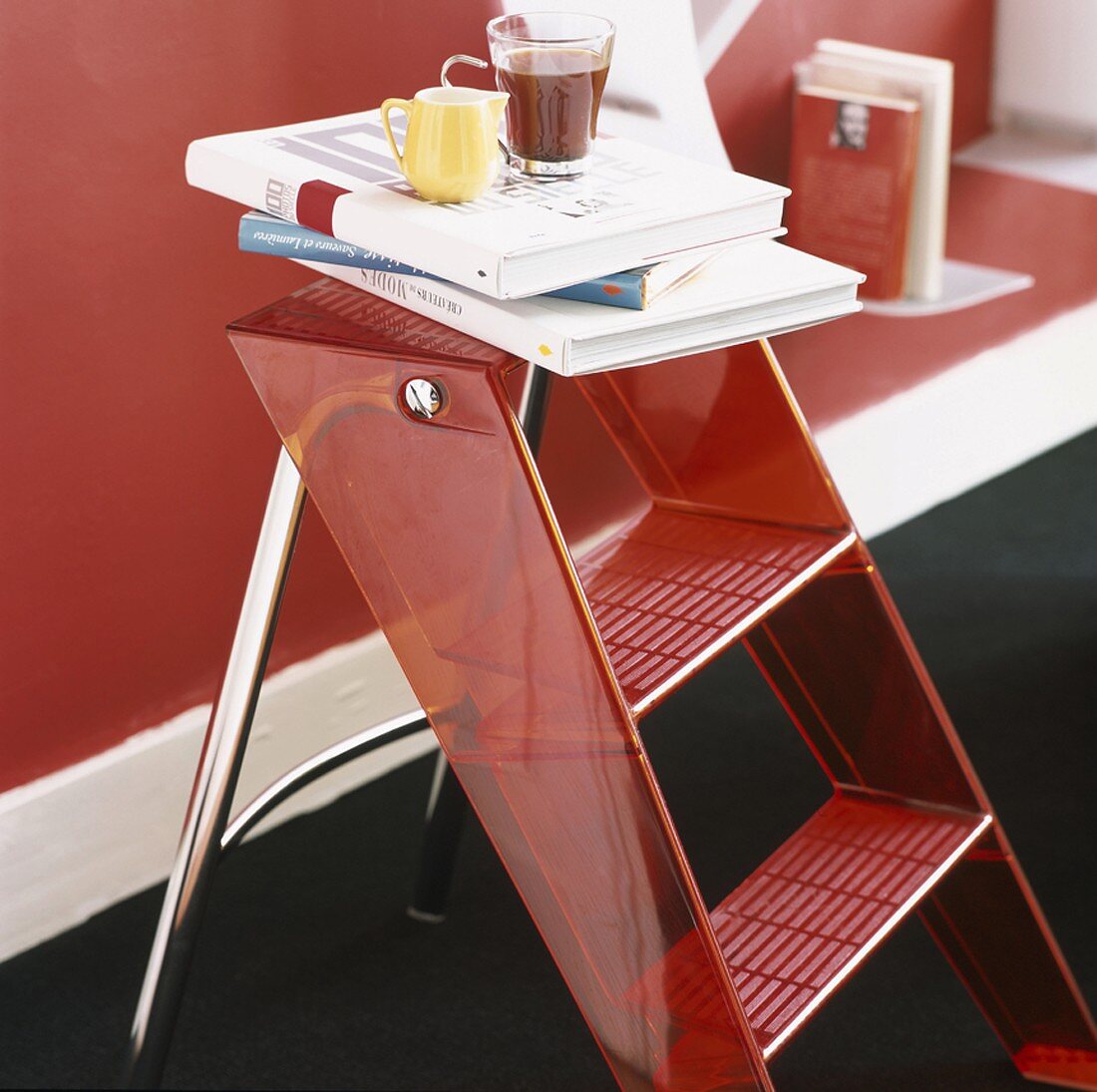 A step ladder with a pile of books on the top step