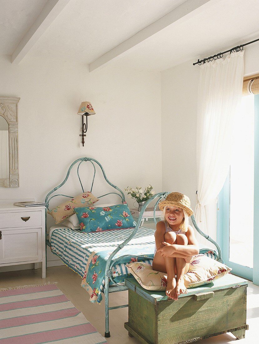 Little girl sitting on trunk in bedroom