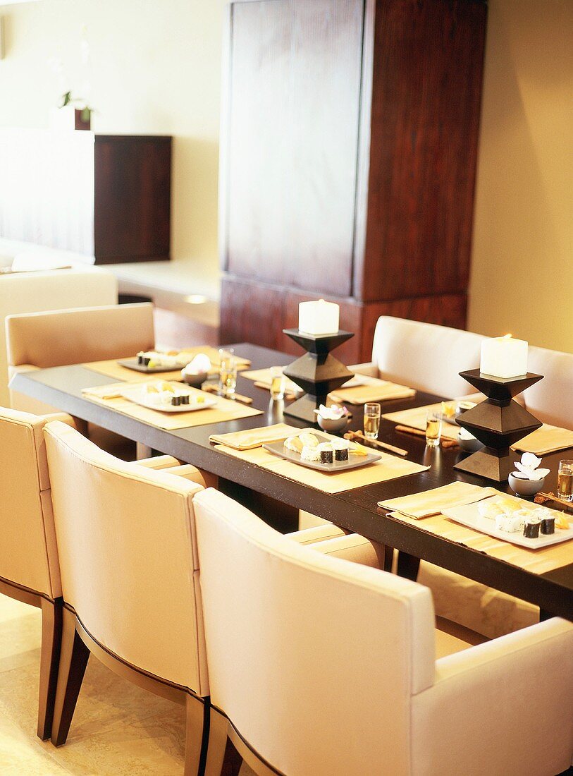 Gedeckter Edelholztisch mit Sesselrepliken, Tischsets und Tischdekoration