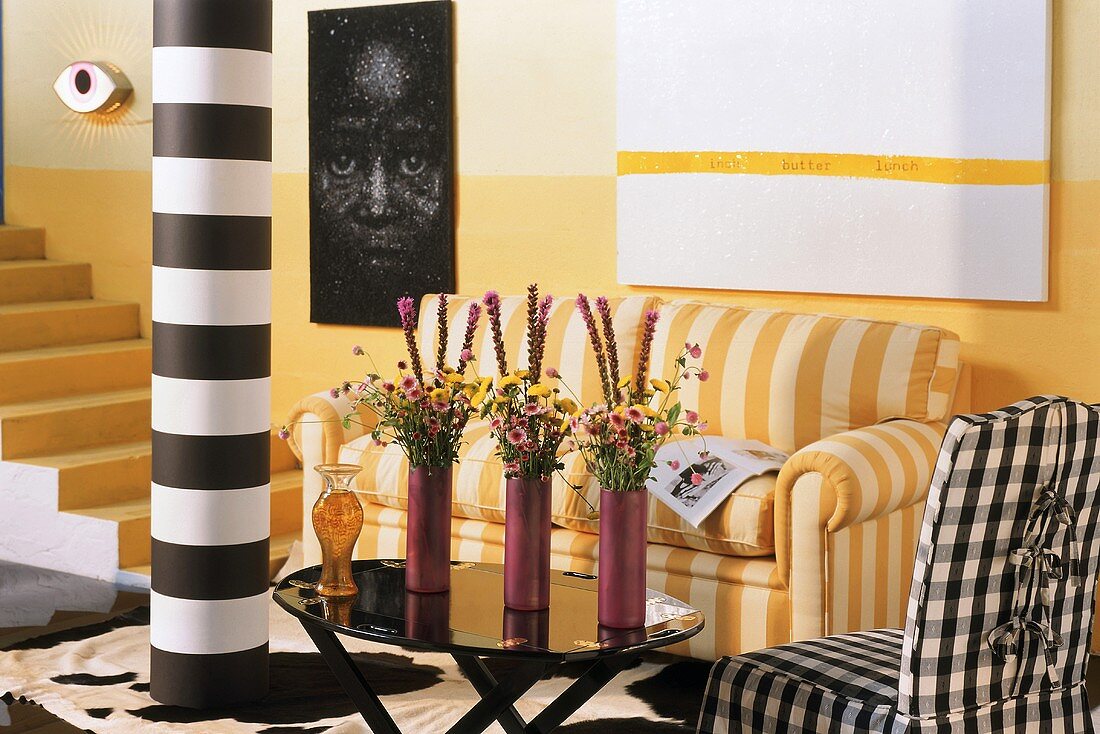 Lively interior with yellow staircase, striped couch in same colour and black and white contrasting accents