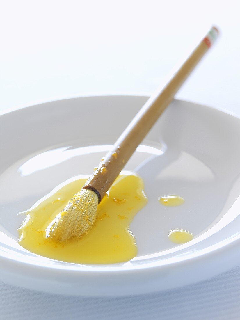 Orange syrup and a brush on a white plate