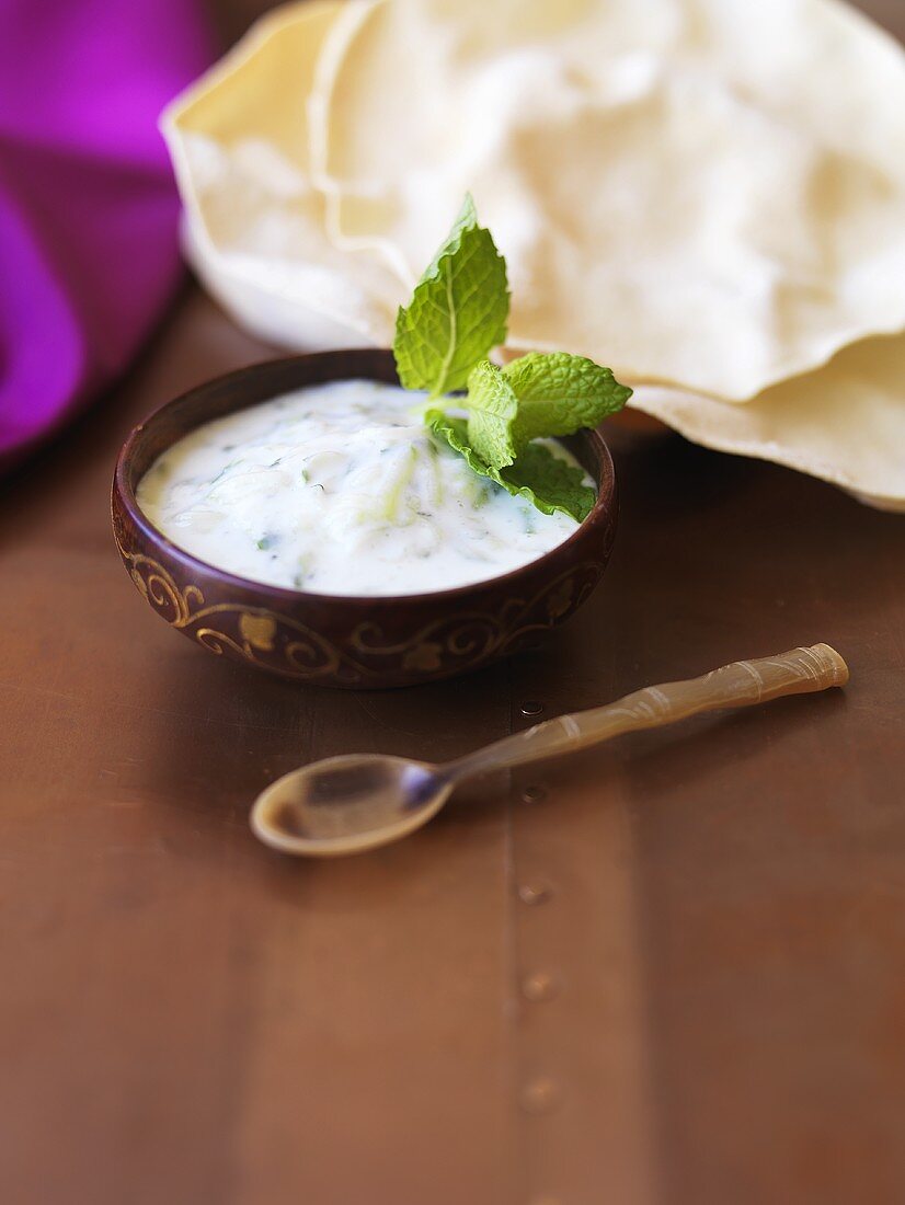 A small bowl of raita with mint leaves