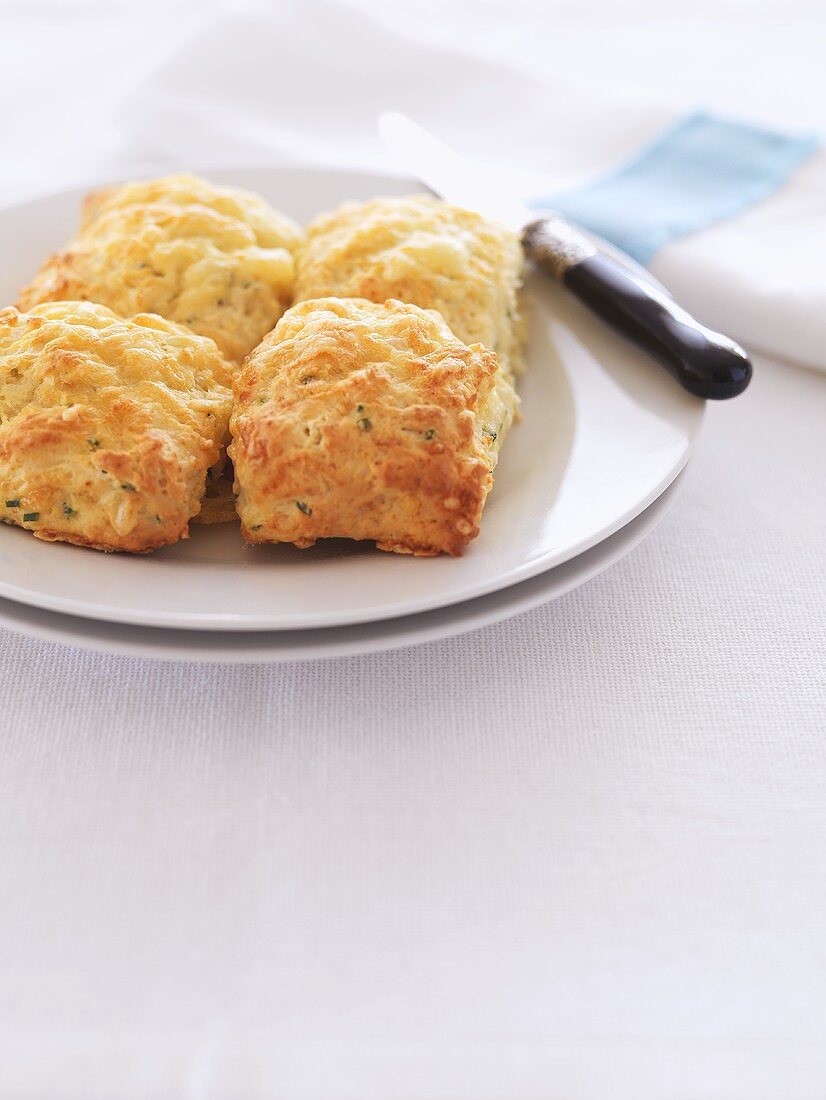 Four golden brown herb and cheese scones on a plate