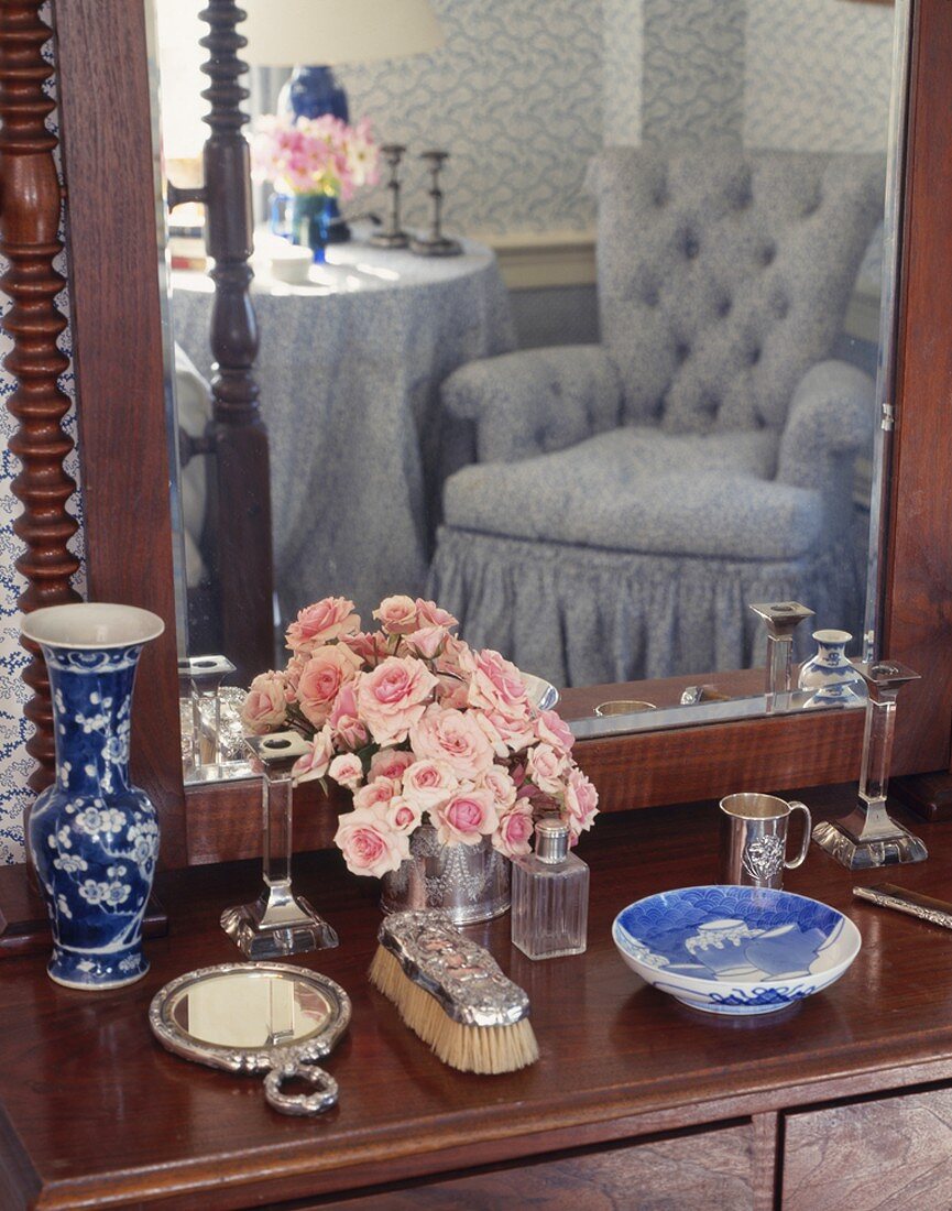 Antique dressing table with romantic armchair reflected in mirror in traditional bedroom