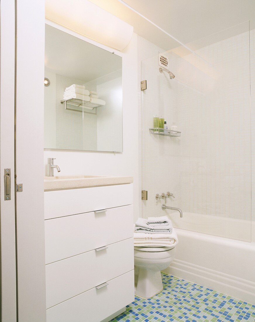 Bright, white bathroom with toilet and mosaic tiles on floor