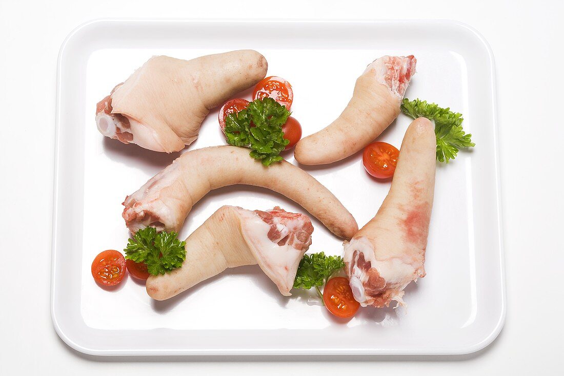 Five pigs' tails on a plate with salad garnish