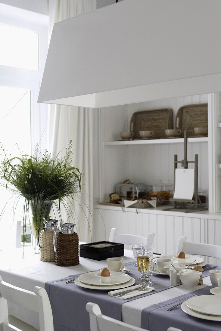 Esszimmerausschnitt mit weißem Einbauschrank, gedecktem Tisch und mit Blick auf das Fenster