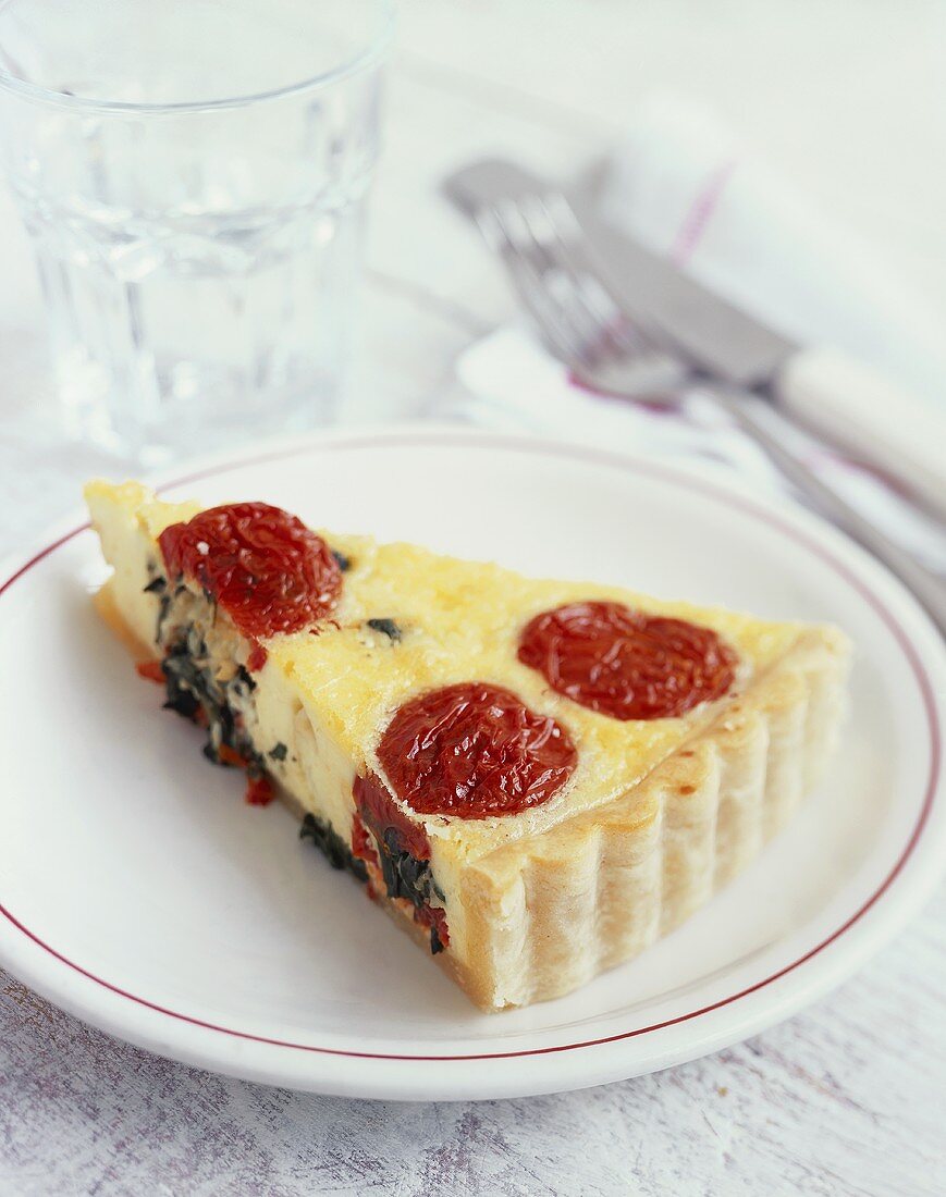 A piece of goat's cheese and tomato quiche with basil