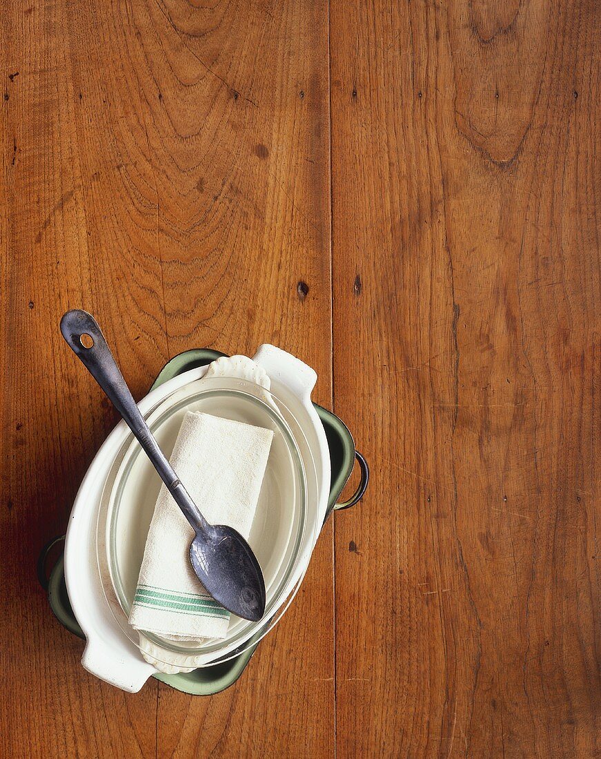 Baking dishes and spoon on wooden background