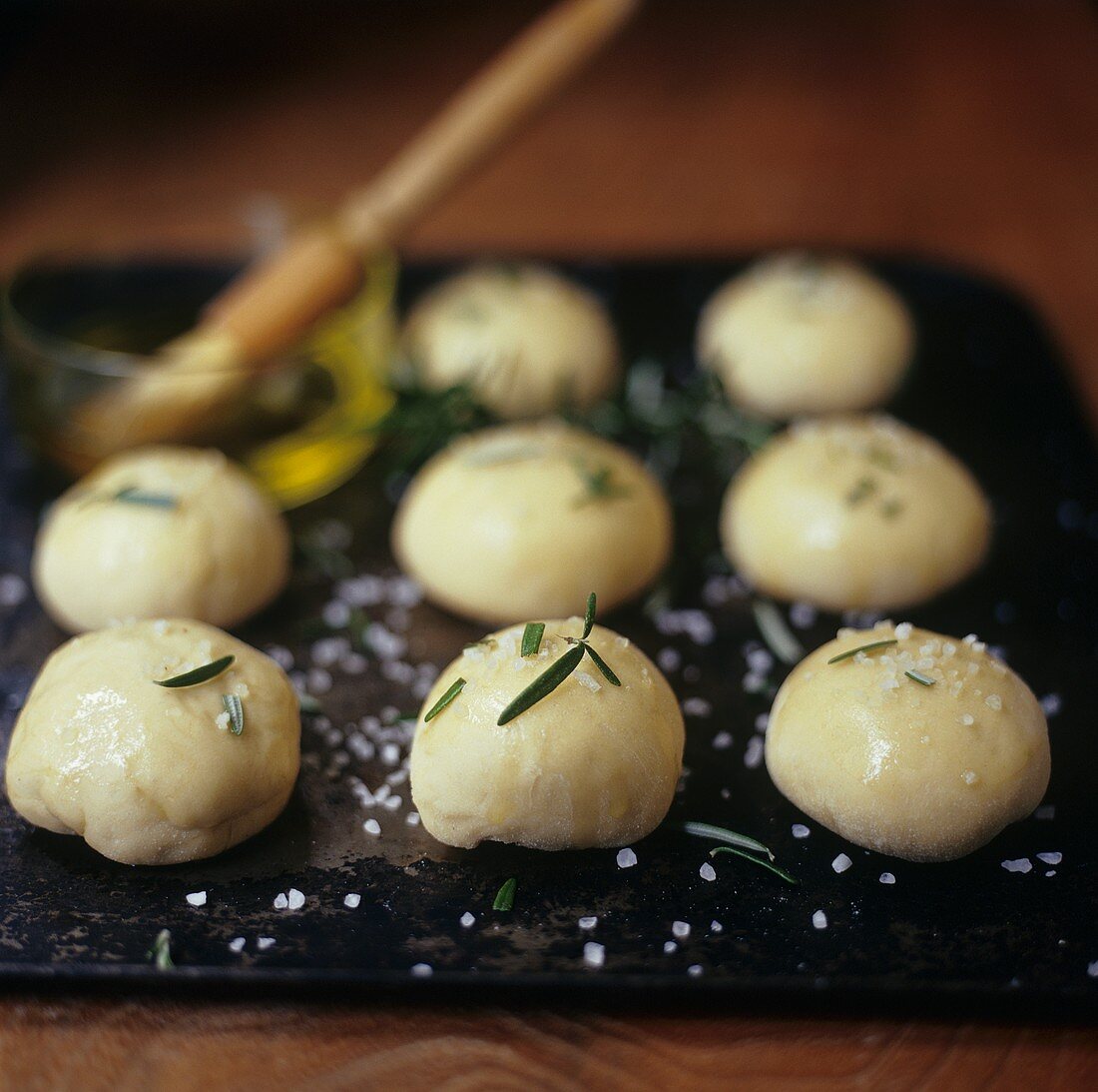 Balls of dough sprinkled with rosemary & salt on baking tray