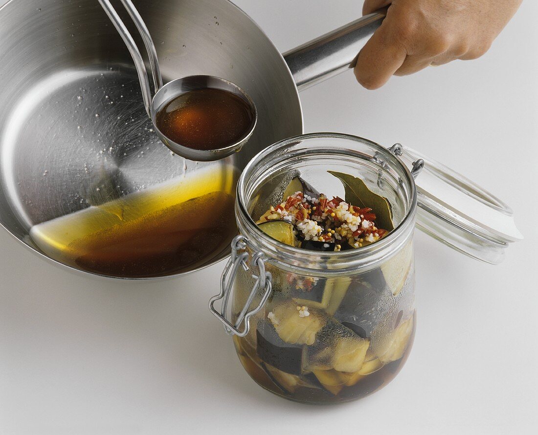 Putting aubergines in honey marinade into a preserving jar