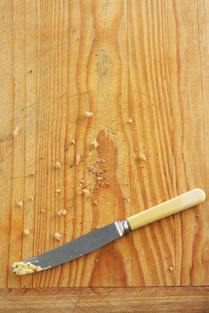 A knife and crumbs on a chopping board