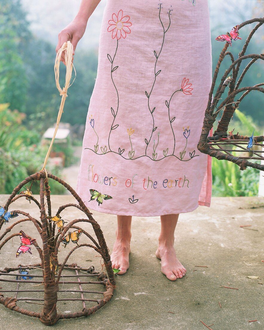 Frau in geblümtem Kleid mit Schmetterlings-Käfigen
