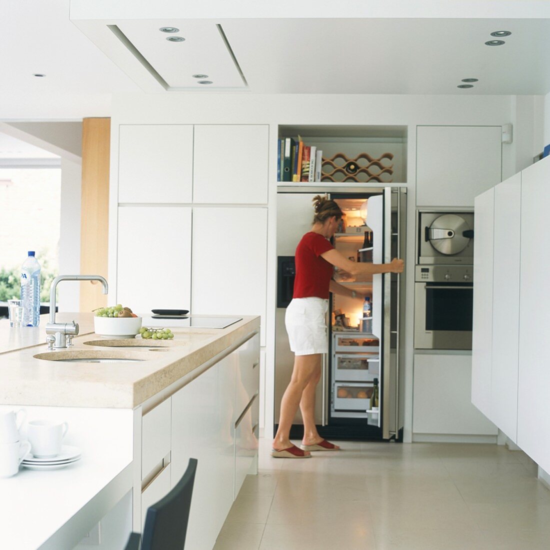 Woman standing in front of open fridge in kitchen