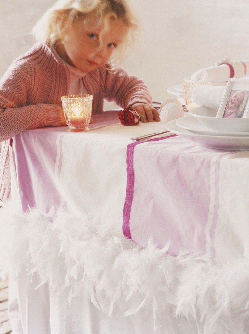 Kleines Mädchen steht an festlich gedecktem Tisch