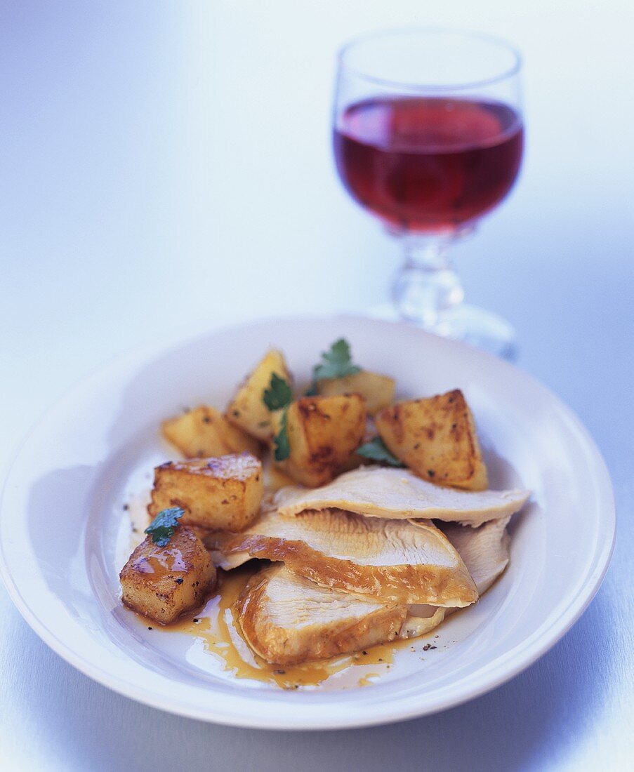 Chicken with diced potatoes and a glass of red wine