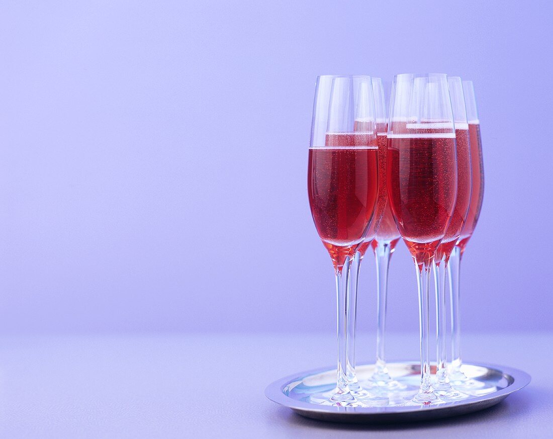 Mehrere Gläser rote Sekt-Cocktails auf einem Tablett