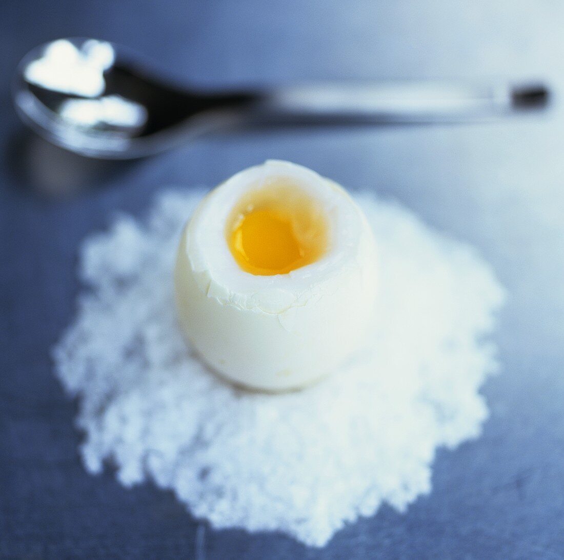 Aufgeschlagenes gekochtes Ei in Häufchen aus groben Salz