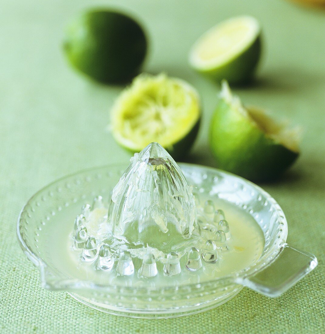 Lime juice in citrus squeezer and squeezed limes