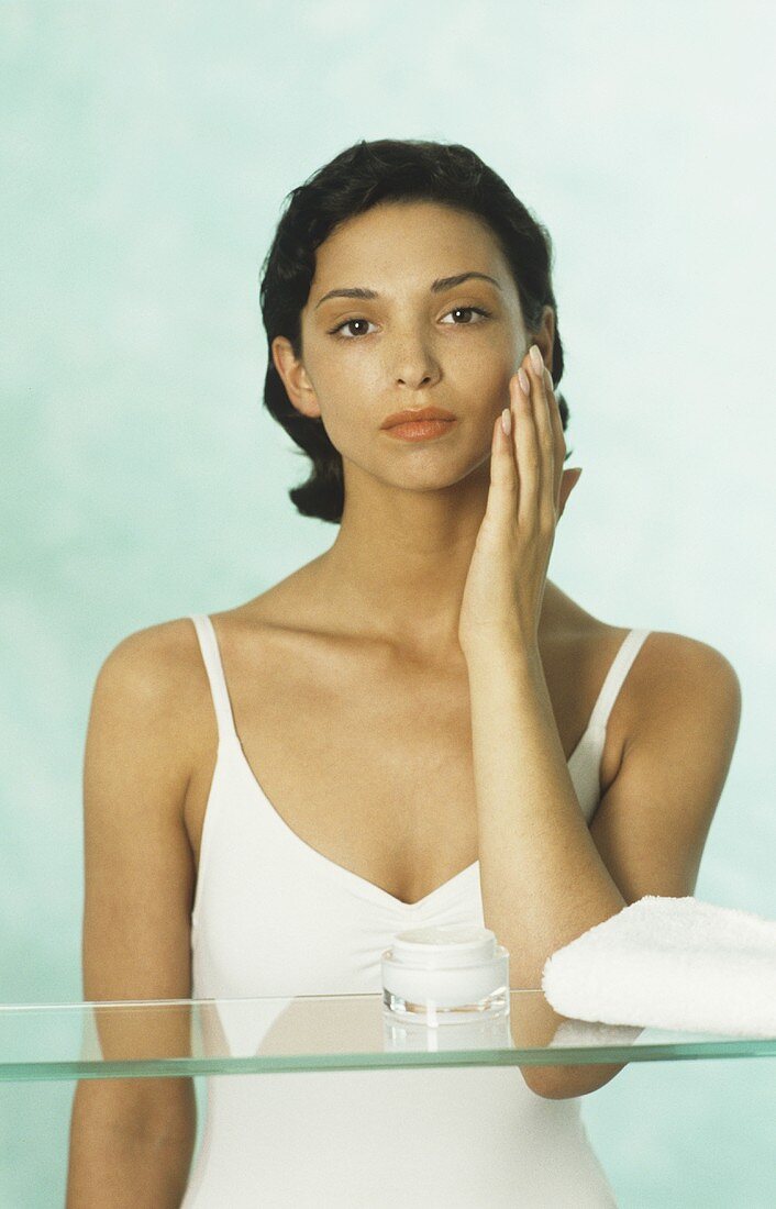 Young woman creaming her face