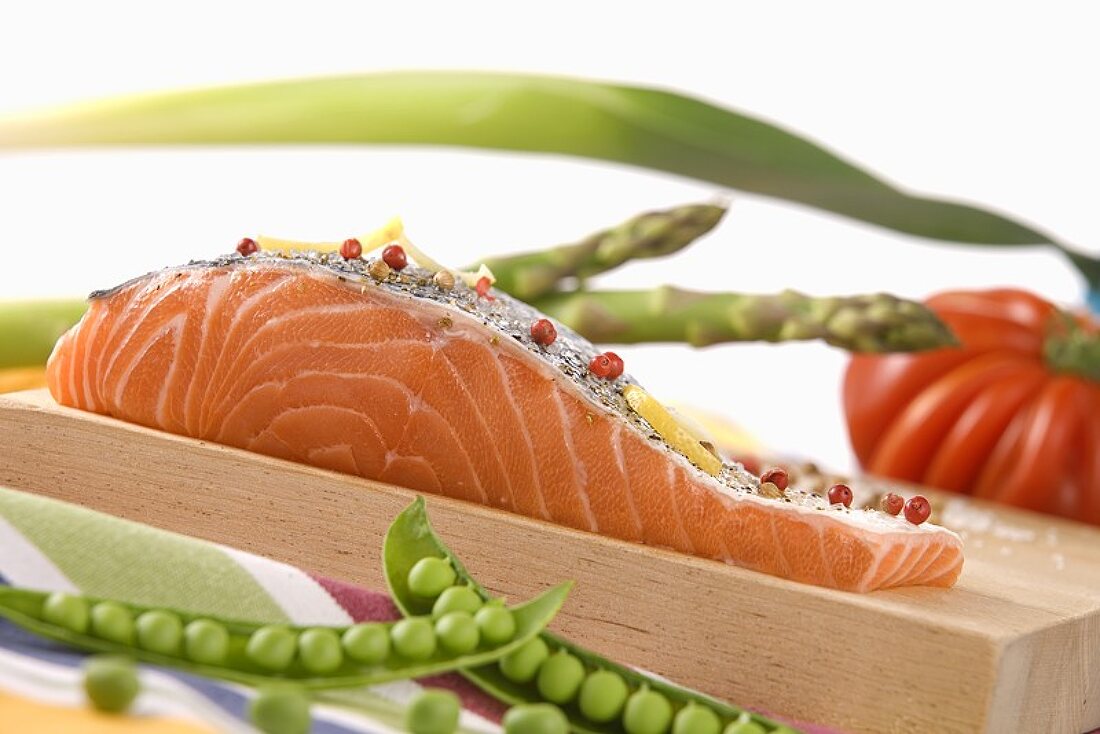 Ein Stück roher Lachs mit Gewürzen auf Holzbrett