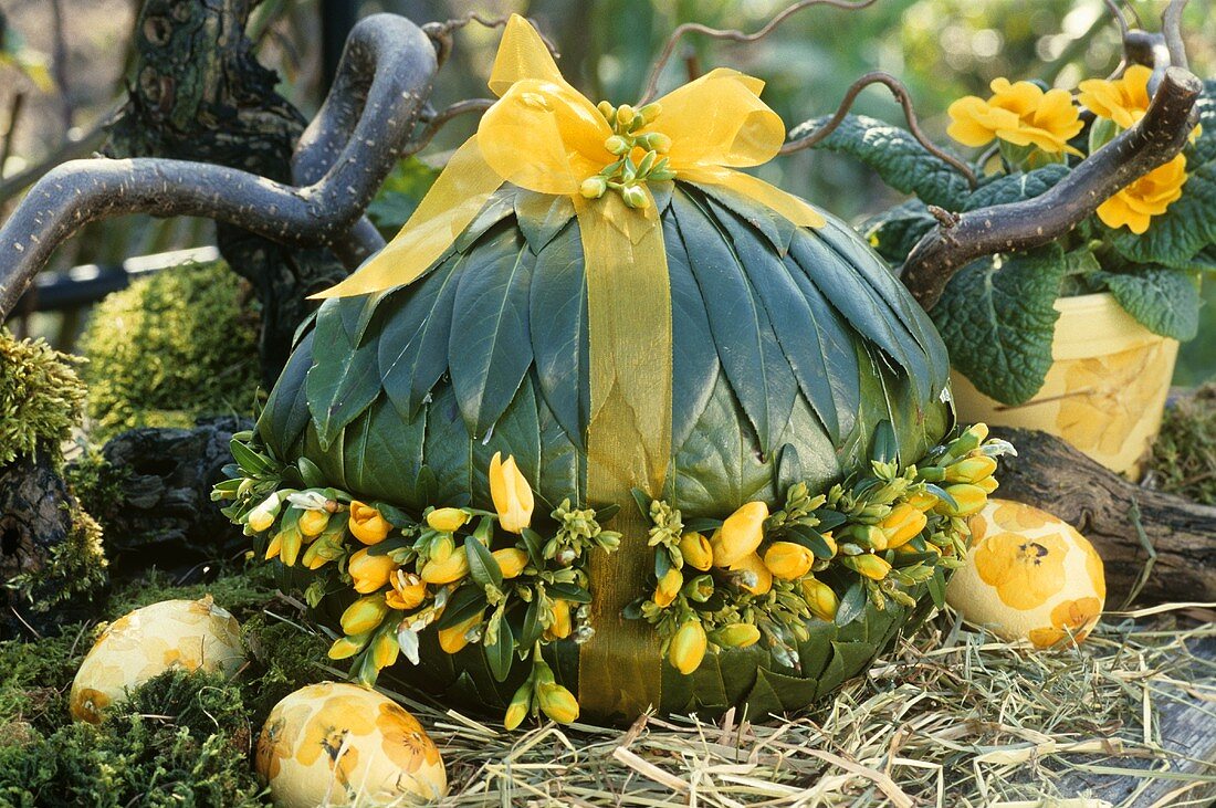 Deko-Ei mit Lorbeerblättern und Fresien verziert zu Ostern