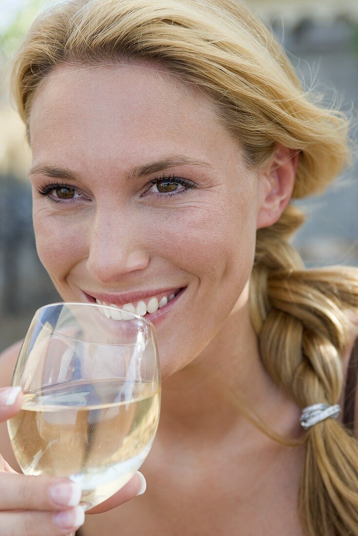 Blonde Frau trinkt ein Glas Weißwein