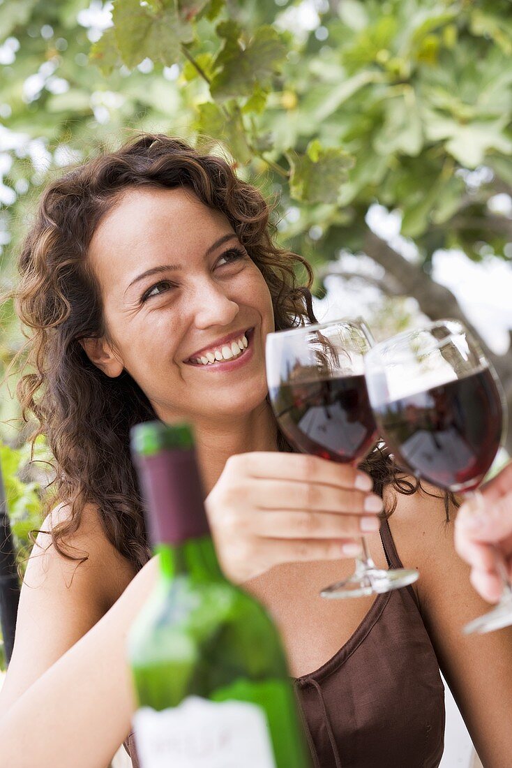 Young woman clinking glass of red wine
