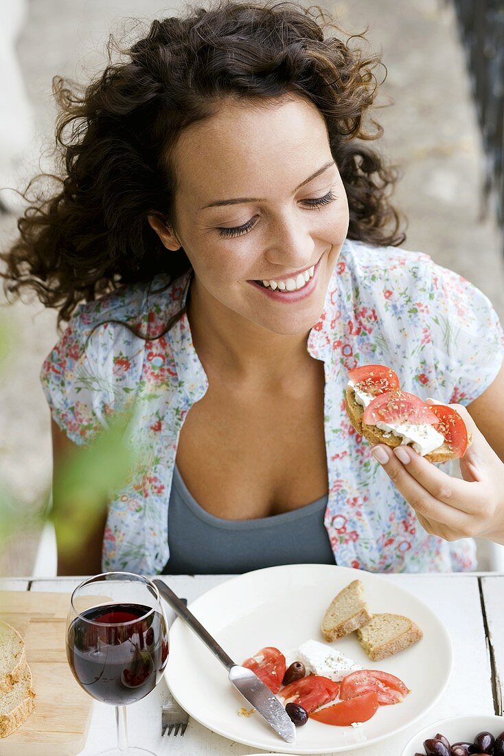 Woman eating sheep's cheese and tomatoes on bread
