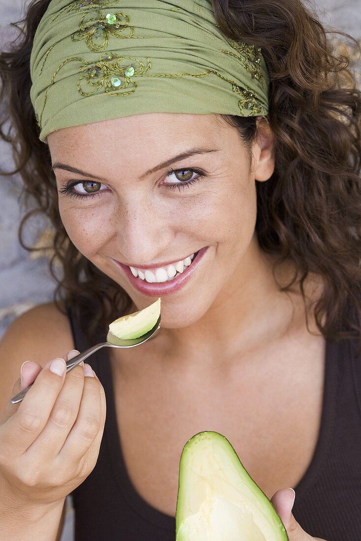 Frau isst eine Avocado mit einem Löffel