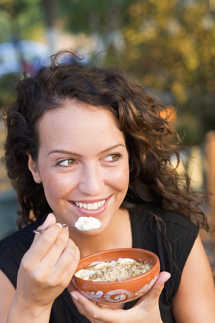 A woman eating yoghurt with honey and grated nuts